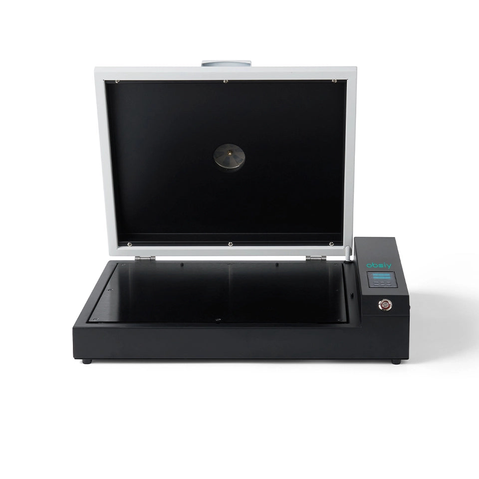 Front view product image of the Obziy DTF Oven with the lid open. The oven has a black base, a white lid, and a small digital control panel on the right side labeled "obziy." The interior curing chamber is visible.